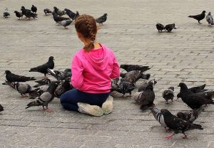 Una niña en un parque rodeada de palomas